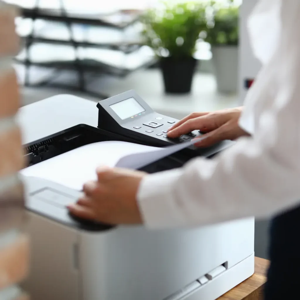 user at a printer collecting their prints